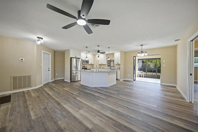 unfurnished living room with hardwood / wood-style flooring, ceiling fan with notable chandelier, and a textured ceiling