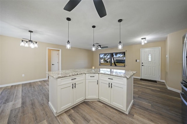 kitchen with light stone counters, a center island, white cabinets, and hardwood / wood-style flooring