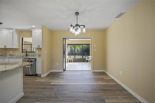 kitchen with white cabinetry, dark wood-type flooring, an inviting chandelier, light stone counters, and stainless steel dishwasher