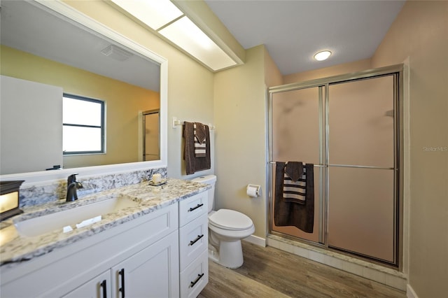 bathroom featuring vanity, toilet, wood-type flooring, and a shower with shower door