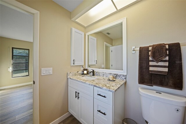 bathroom with toilet, vanity, and hardwood / wood-style flooring