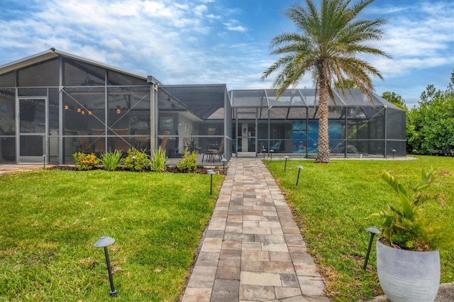 rear view of property featuring a yard and glass enclosure