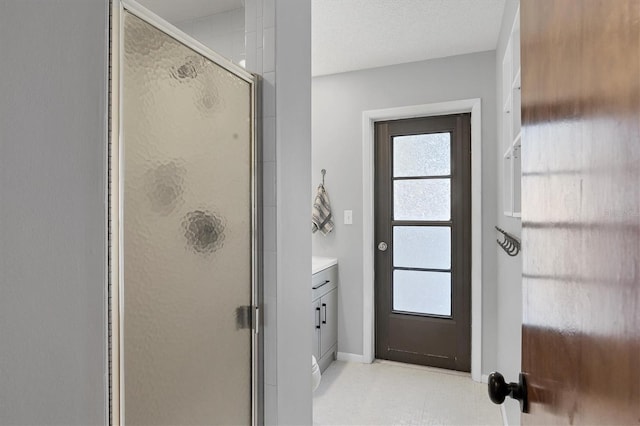 bathroom with vanity, a shower with shower door, and a textured ceiling