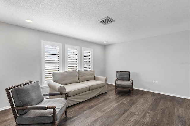 living room with a textured ceiling and dark hardwood / wood-style flooring