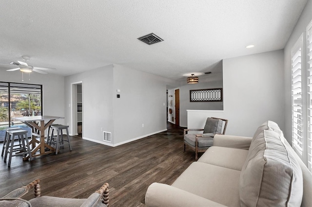 living room featuring ceiling fan, dark wood-type flooring, and a textured ceiling