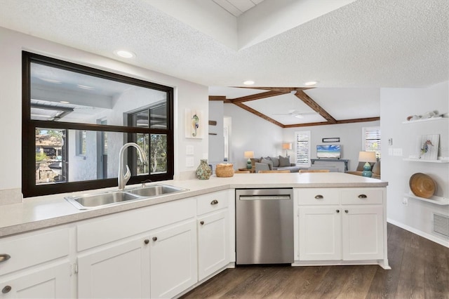 kitchen featuring kitchen peninsula, stainless steel dishwasher, sink, a textured ceiling, and vaulted ceiling with beams