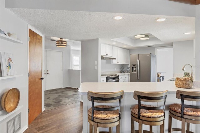 kitchen with appliances with stainless steel finishes, a textured ceiling, white cabinets, sink, and kitchen peninsula