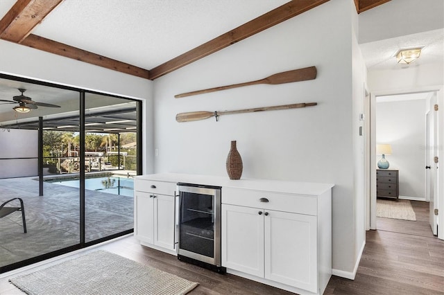 bar with white cabinetry, beverage cooler, a textured ceiling, and lofted ceiling