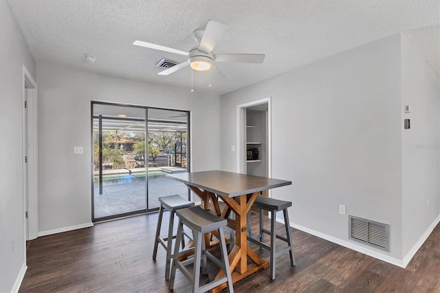 dining space with ceiling fan, a textured ceiling, and dark hardwood / wood-style flooring