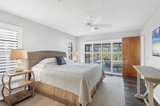 bedroom featuring ceiling fan, dark hardwood / wood-style flooring, access to exterior, and a textured ceiling