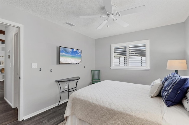 bedroom with a textured ceiling, dark hardwood / wood-style floors, and ceiling fan