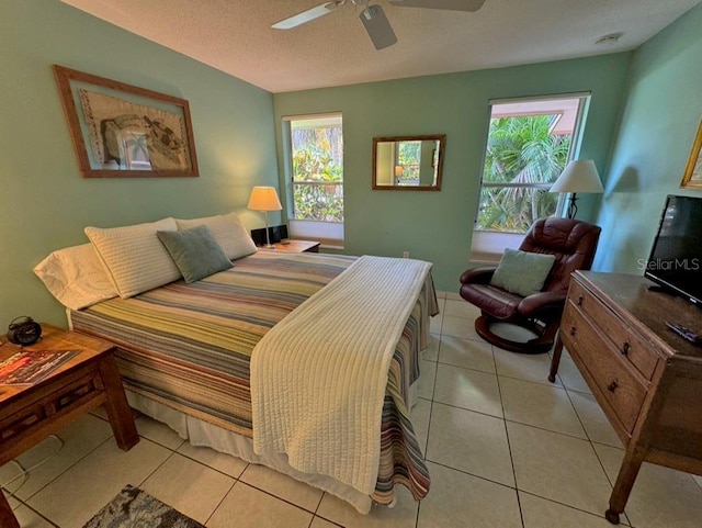 bedroom with ceiling fan, light tile patterned flooring, and a textured ceiling