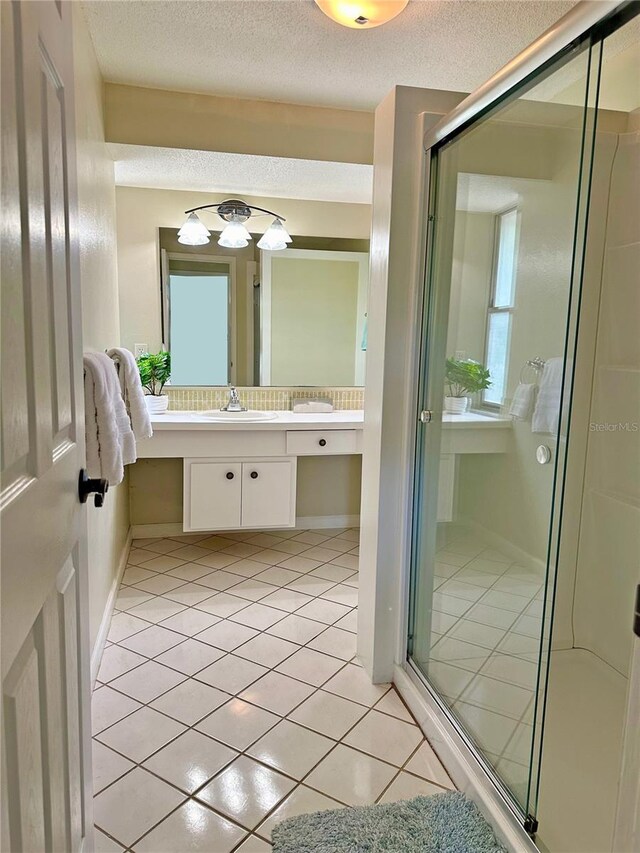 bathroom with tile patterned floors, vanity, a shower with shower door, and a textured ceiling