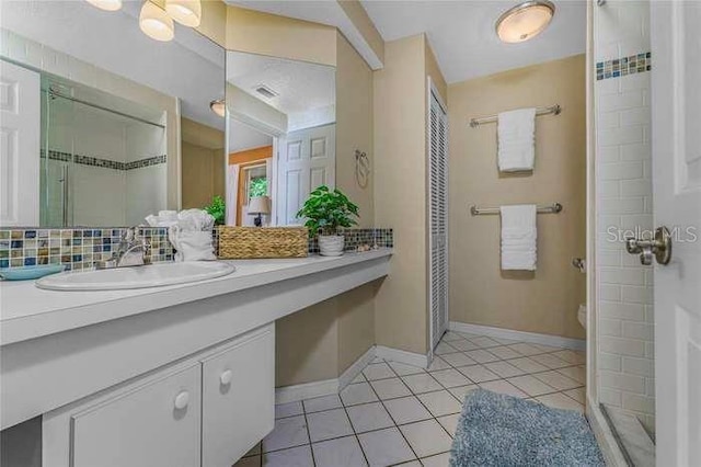 bathroom featuring tasteful backsplash, vanity, a shower, tile patterned flooring, and toilet