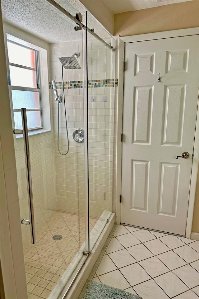 bathroom featuring tile patterned flooring, an enclosed shower, and a textured ceiling