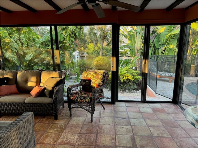 sunroom / solarium featuring beam ceiling and ceiling fan