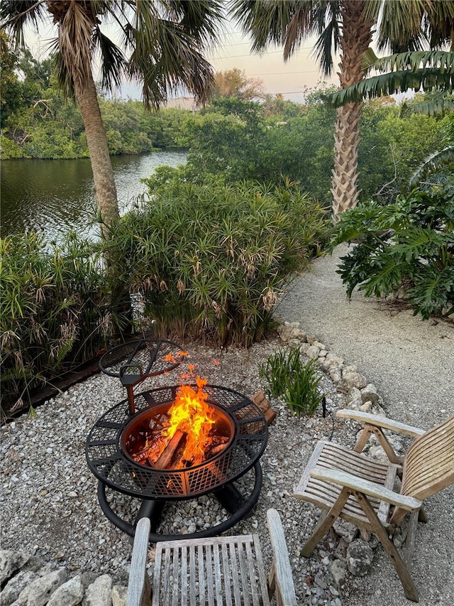 yard at dusk with a water view and an outdoor fire pit