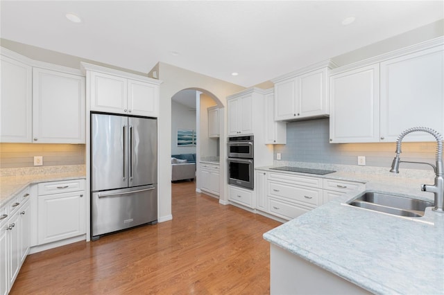 kitchen featuring appliances with stainless steel finishes, light hardwood / wood-style floors, white cabinetry, and sink