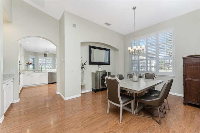 dining room featuring light hardwood / wood-style flooring, ceiling fan with notable chandelier, and sink