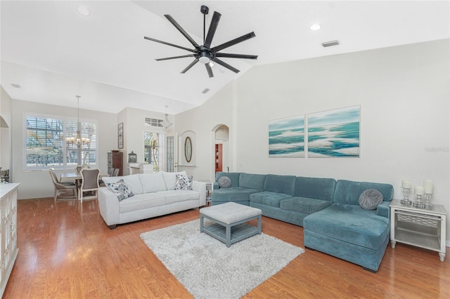 living room with hardwood / wood-style floors, ceiling fan with notable chandelier, and lofted ceiling