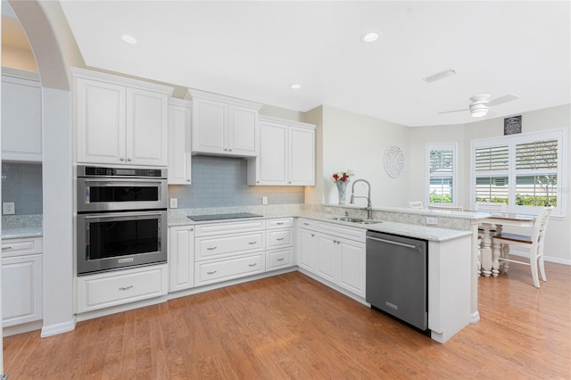 kitchen featuring kitchen peninsula, white cabinetry, stainless steel appliances, and light hardwood / wood-style flooring