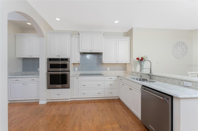 kitchen featuring sink, stainless steel appliances, backsplash, light hardwood / wood-style floors, and white cabinets