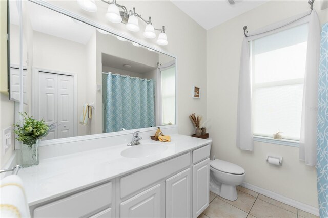 bathroom with tile patterned flooring, vanity, toilet, and a healthy amount of sunlight