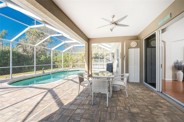 view of pool with glass enclosure, ceiling fan, and a patio area