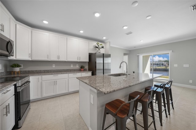 kitchen featuring a kitchen bar, appliances with stainless steel finishes, light stone countertops, sink, and an island with sink