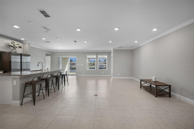 kitchen featuring light stone counters, a breakfast bar, crown molding, sink, and stainless steel refrigerator