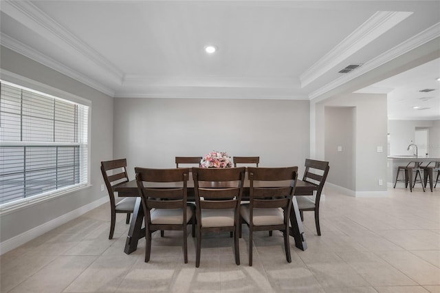 dining room featuring a raised ceiling, crown molding, and light tile patterned floors