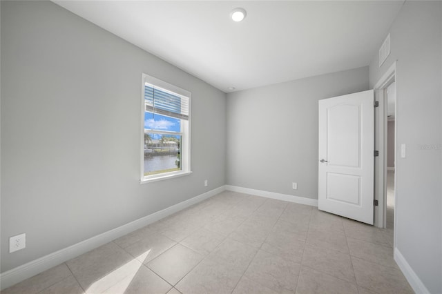 unfurnished room featuring a water view and light tile patterned floors