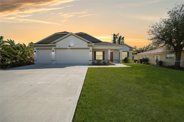 view of front of house featuring a yard, central AC unit, and a garage