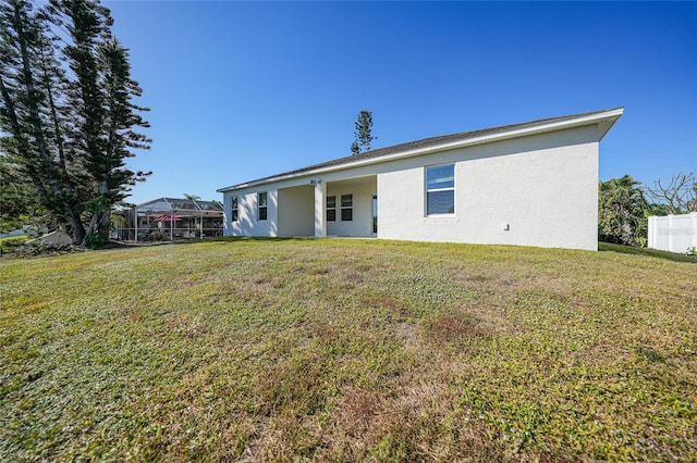 rear view of property featuring a lawn and glass enclosure