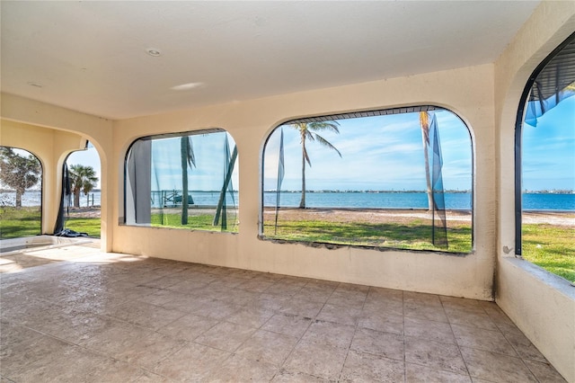 unfurnished sunroom featuring a water view