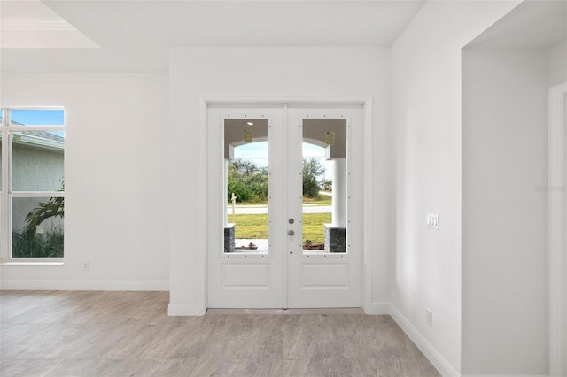 doorway with french doors, light hardwood / wood-style floors, and a healthy amount of sunlight