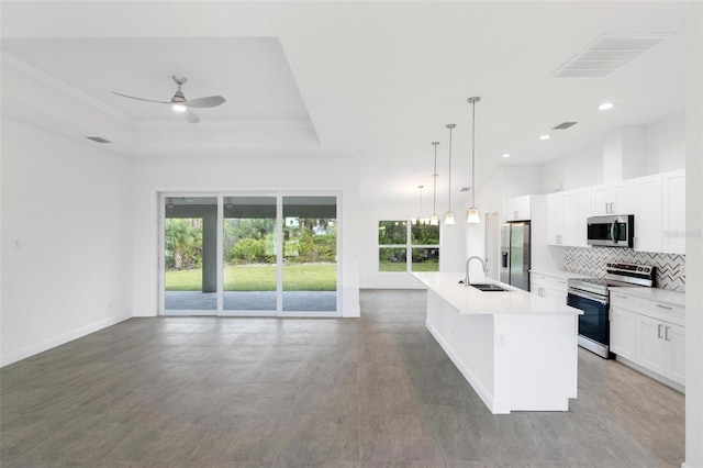 kitchen with hanging light fixtures, ceiling fan, an island with sink, white cabinetry, and stainless steel appliances