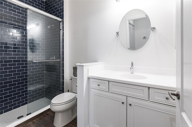 bathroom with a shower with door, vanity, and toilet