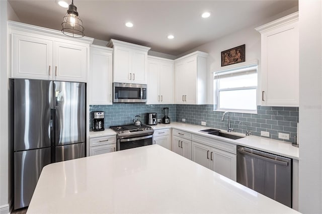 kitchen with decorative backsplash, appliances with stainless steel finishes, sink, pendant lighting, and white cabinetry