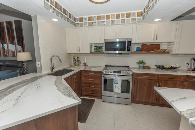 kitchen featuring sink, light stone countertops, stainless steel appliances, and light tile patterned floors