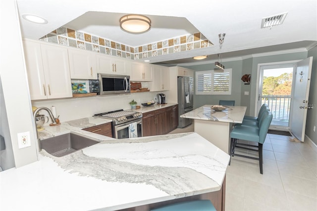 kitchen with a kitchen breakfast bar, sink, ornamental molding, white cabinetry, and stainless steel appliances