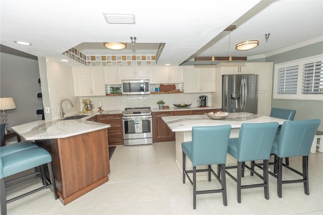 kitchen featuring a kitchen bar, ornamental molding, stainless steel appliances, sink, and a center island