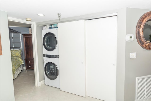 laundry area featuring stacked washer and dryer and light tile patterned floors