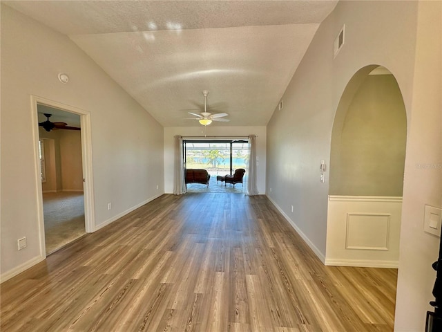 unfurnished living room with a textured ceiling, ceiling fan, hardwood / wood-style floors, and lofted ceiling