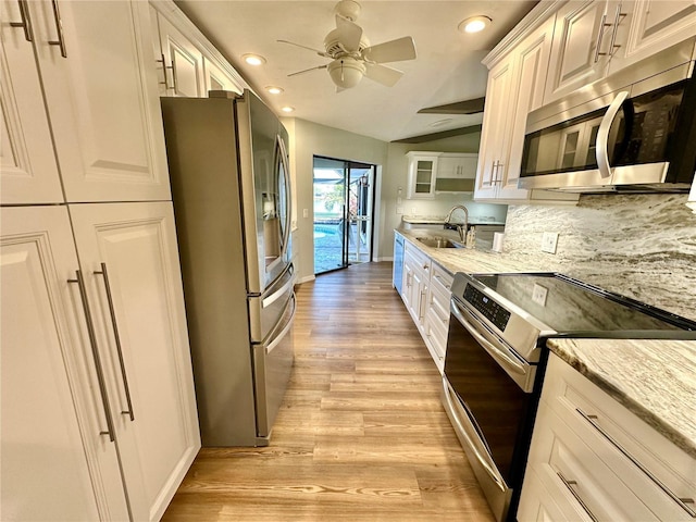 kitchen with sink, light hardwood / wood-style floors, light stone counters, white cabinetry, and stainless steel appliances