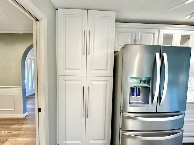 kitchen featuring stainless steel refrigerator with ice dispenser, light wood-type flooring, and white cabinetry