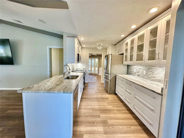 kitchen featuring tasteful backsplash, stainless steel appliances, sink, light hardwood / wood-style floors, and white cabinetry