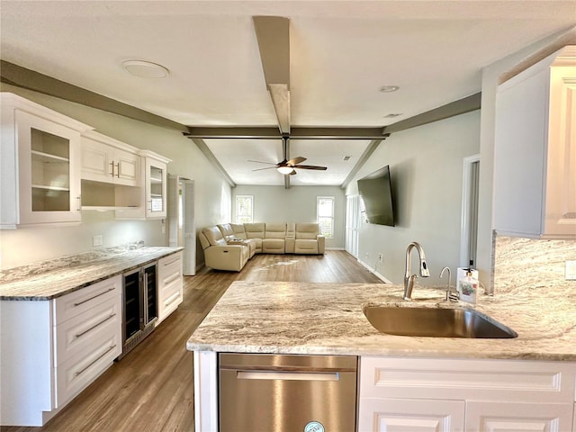 kitchen featuring white cabinets, lofted ceiling with beams, light stone counters, and sink