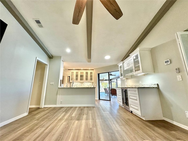 kitchen with beam ceiling, ceiling fan, wine cooler, light stone counters, and white cabinets