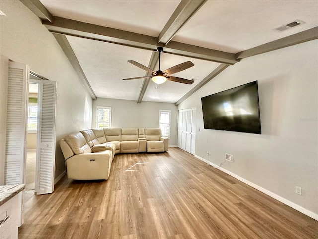 unfurnished living room with light wood-type flooring, vaulted ceiling with beams, and ceiling fan